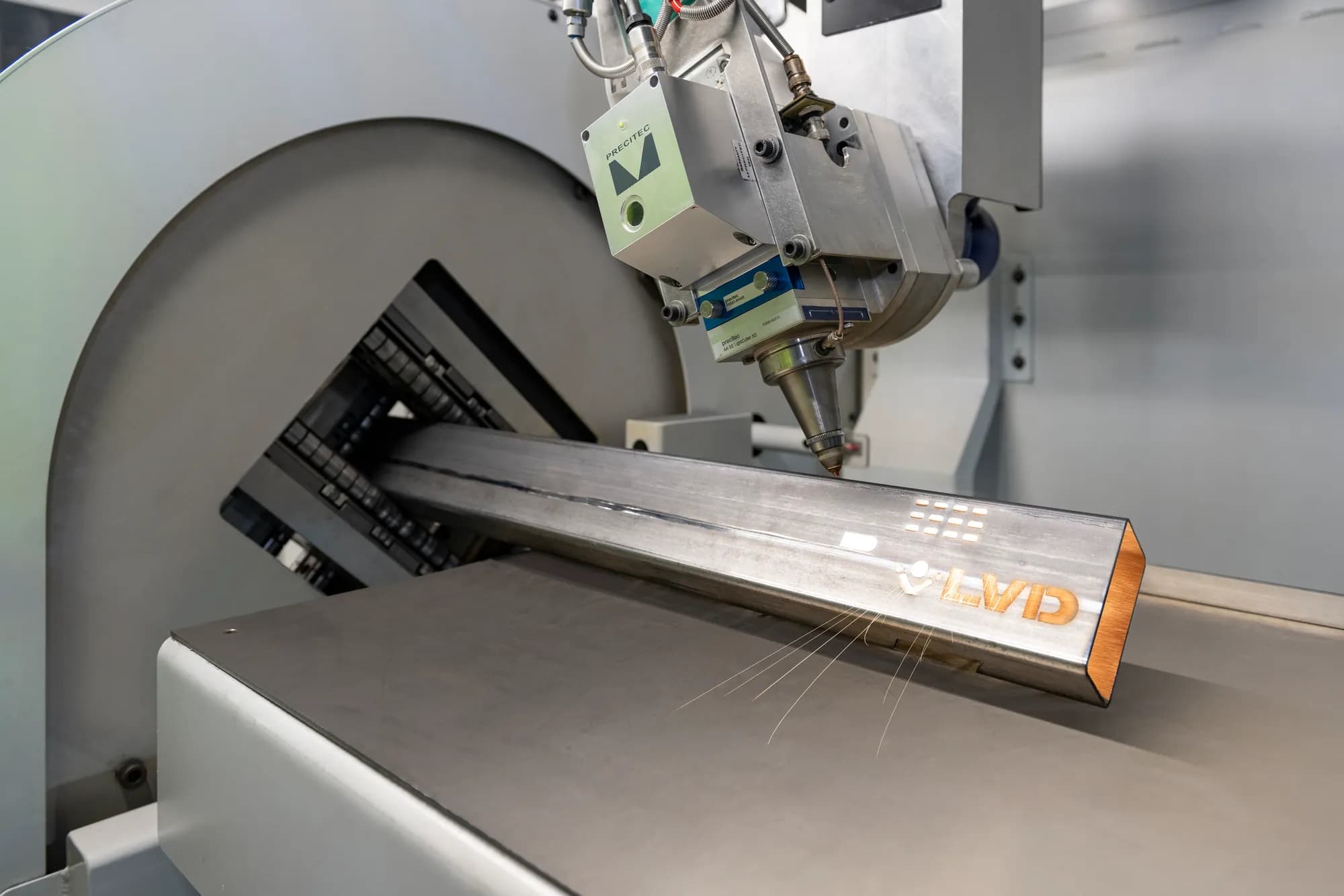 An LVD tube laser cutting a profile in a steel box section, sparks trailing from the cut