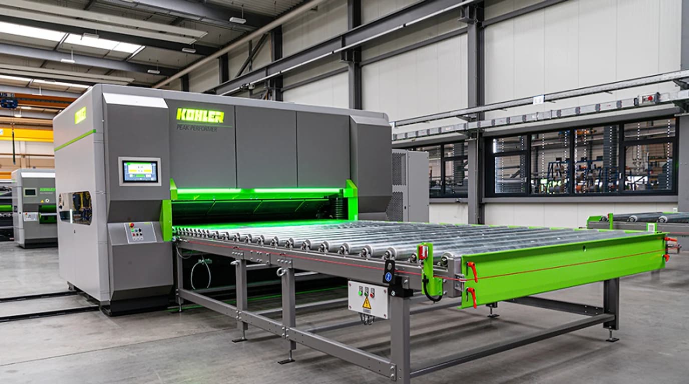 A KOHLER Peak Performer part levelling machine with its roller conveyor on a factory floor