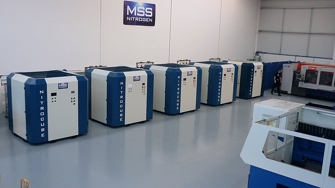 A row of MSS NitroCube nitrogen generators installed beside a laser cutting machine