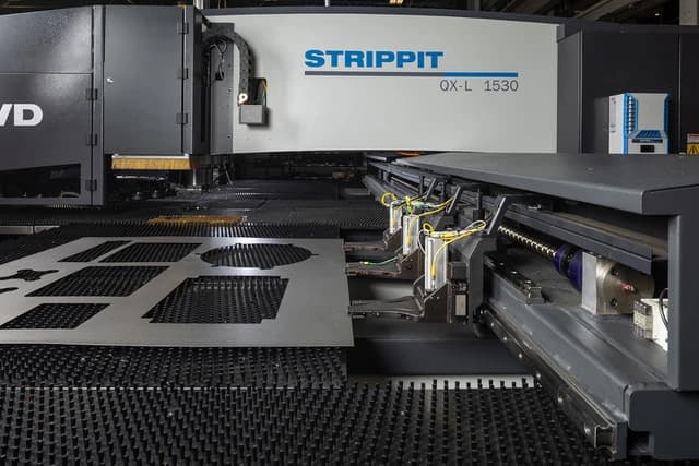 Strippit QX-L 1530 with a punched sheet held on the brush table by the programmable work clamps