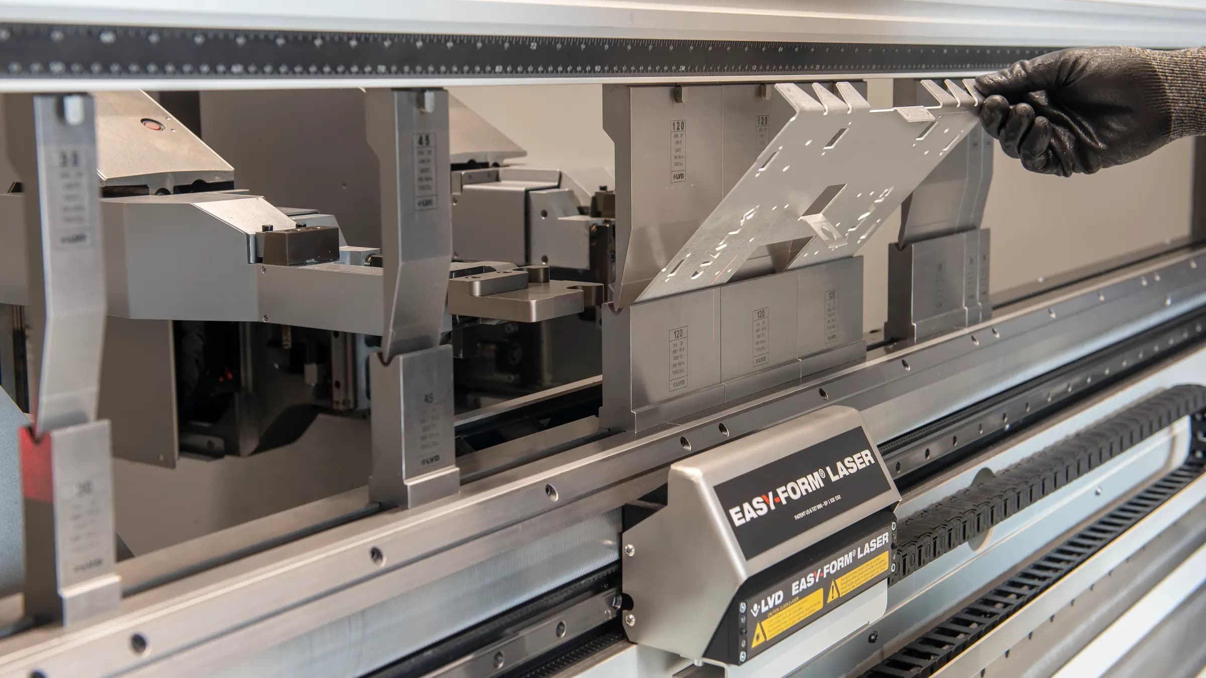 A CNC press brake bending a steel sheet into a crisp V-bend against the die
