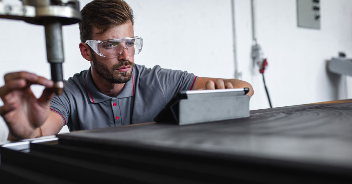 Young engineer setup laser cutter for work in metalwork workshop.